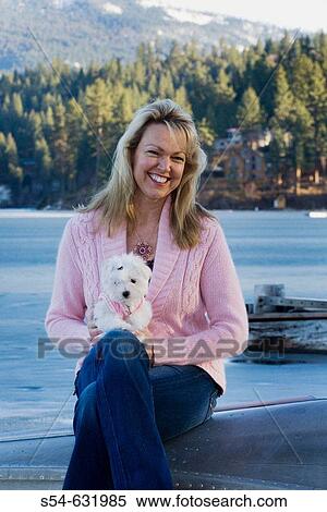 Stock Photography - A woman and her two-month-old Maltese Poodle at the lake.. Fotosearch