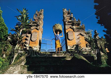 A woman carrying a basket walking between two traditional gates at sunset View Large Photo Image Stock Image - A woman carrying a basket walking between two traditional gates at sunset. Fotosearch