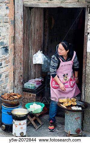 A woman cooking food for sale to tourists in Hongcun heritage village in Huizhou region, Anhui. View Large Photo Image Picture - A woman cooking food for sale to tourists in Hongcun heritage village in Huizhou region, Anhui.. Fotosearch