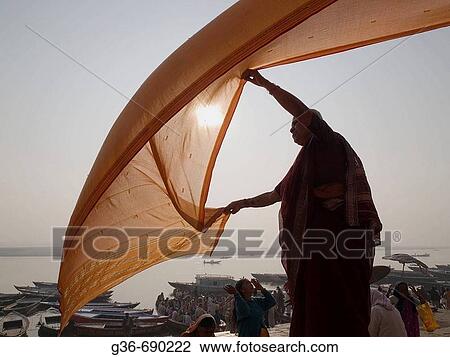 A woman dries a wet sari in the early morning sun after bathing in the Ganga river (in accordance with the Hindu belief that such bathing will wash away her sins) in Varanasi, India, a sacred Hindu pilgrimage site. View Large Photo Image Stock Image - A woman dries a wet sari in the early morning sun after bathing in the Ganga river (in accordance with the Hindu belief that such bathing will wash away her sins) in Varanasi, India, a sacred Hindu pilgrimage site.. Fotosearch
