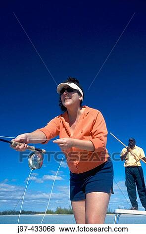 A woman enjoying the sport of fly fishing with her guide poling throught the flats of Blanket Sound off Kamalama Cay, Andros, Bahamas, Atlantic Ocean View Large Photo Image Stock Photo - A woman enjoying the sport of fly fishing with her guide poling throught the flats of Blanket Sound off Kamalama Cay, Andros, Bahamas, Atlantic Ocean. Fotosearch