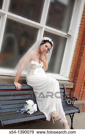 Stock Photo - A woman in a bridal gown, sitting on a bench. Fotosearch