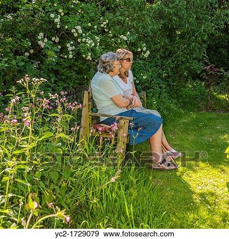 A woman in her 30's talks to her mother in law in her 70's in a Uk cottage garden View Large Photo Image Stock Photo - A woman in her 30's talks to her mother in law in her 70's in a Uk cottage garden. Fotosearch