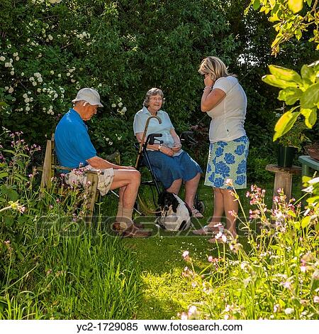 A woman in her 30's talks to her parents in law in their 70's in a Uk cottage garden View Large Photo Image Stock Photography - A woman in her 30's talks to her parents in law in their 70's in a Uk cottage garden. Fotosearch