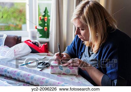 A woman in her 30's wrapping Christmas presents up at home in the Uk. View Large Photo Image Stock Photograph - A woman in her 30's wrapping Christmas presents up at home in the Uk.. Fotosearch