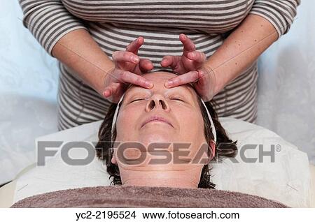 Picture - A woman in her early sixties having a facial and make up beauty treatment by a beauty therapist.. Fotosearch