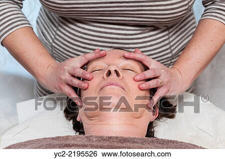 Stock Photograph - A woman in her early sixties having a facial and make up beauty treatment by a beauty therapist.. Fotosearch