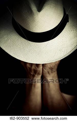 Stock Image - A woman ismeditating under his Panama hat. Fotosearch