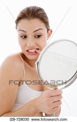 Stock Image - A woman looking at teeth with mirror. Fotosearch