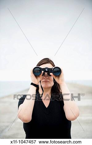 Stock Photo - A woman looking through a pair of binoculars. Fotosearch