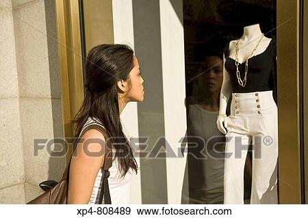 Stock Photo - A woman looks from the street through the window of a boutique at some clothing display? s. Boston, Massachusetts, USA. Fotosearch
