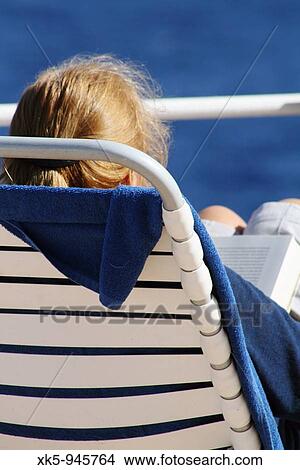 Picture - A woman reading on the deck of a cruise ship around the Atlantic ocean.. Fotosearch
