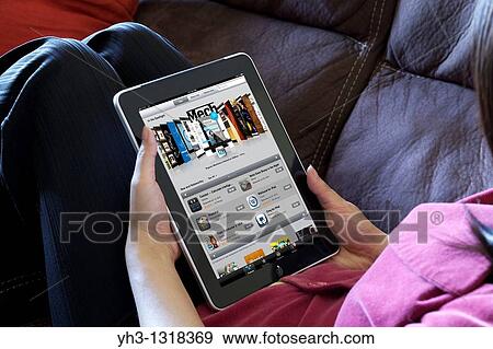 A woman relaxing while browsing iPad application store from an iPad View Large Photo Image Stock Photo - A woman relaxing while browsing iPad application store from an iPad. Fotosearch