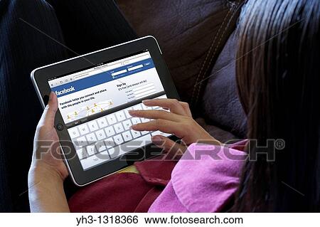 A woman relaxing while using iPad to check her Facebook page View Large Photo Image Stock Photograph - A woman relaxing while using iPad to check her Facebook page. Fotosearch
