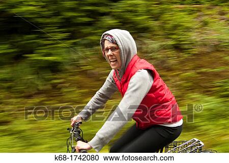 a woman rides a bicycle on a road through a forest View Large Photo Image Stock Image - a woman rides a bicycle on a road through a forest. Fotosearch