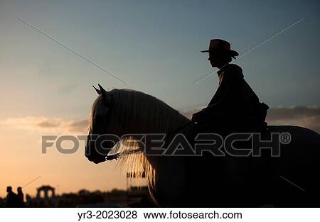 Stock Photo - A woman rides a horse during the pilgrimage to the Hermitage of the Virgin of Rocio, in Almonte, Donana National Park, Huelva province, Andalusia, Spain. Fotosearch