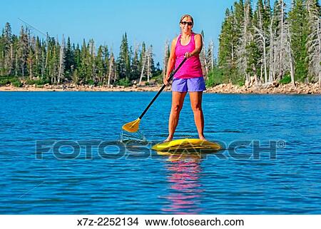 A woman riding the Standup Paddle Board at Lake Cleveland on Mount Harrison high on in the Albion Mountains in southern Idaho. View Large Photo Image Picture - A woman riding the Standup Paddle Board at Lake Cleveland on Mount Harrison high on in the Albion Mountains in southern Idaho.. Fotosearch
