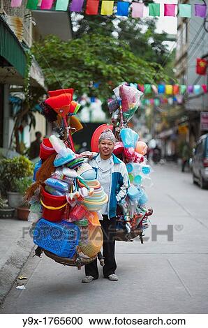 A woman selling plastic goods on the street balancing them on baskets on her shoulder View Large Photo Image Stock Image - A woman selling plastic goods on the street balancing them on baskets on her shoulder. Fotosearch