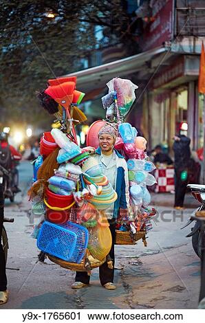 A woman selling plastic goods on the street balancing them on baskets on her shoulder View Large Photo Image Stock Image - A woman selling plastic goods on the street balancing them on baskets on her shoulder. Fotosearch
