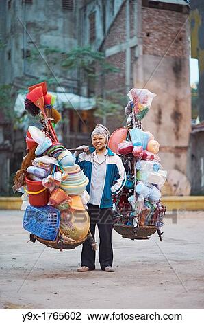 A woman selling plastic goods on the street balancing them on baskets on her shoulder View Large Photo Image Stock Image - A woman selling plastic goods on the street balancing them on baskets on her shoulder. Fotosearch