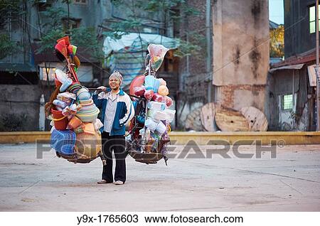 A woman selling plastic goods on the street balancing them on baskets on her shoulder View Large Photo Image Stock Image - A woman selling plastic goods on the street balancing them on baskets on her shoulder. Fotosearch