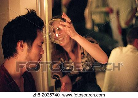 Stock Image - A woman smashes plastic bubbles on a man's head at a house party in Los Angeles. Fotosearch