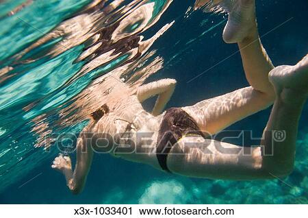 Stock Image - A woman swimming underwater. Fotosearch