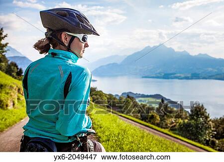 Stock Photo - A woman taking a break while moutain biking in the area of Seebodenalp - Weggis on Mount Rigi in Switzerland.. Fotosearch