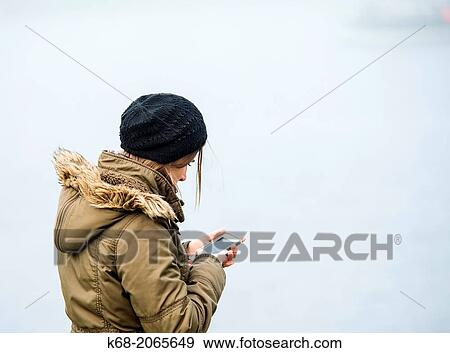 Stock Photo - A woman uses her mobile phone in the fog on False Creek in Vancouver, BC, Canada.. Fotosearch