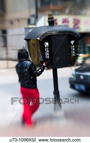 A woman using a public telephone in downtown Nanjing, China. View Large Photo Image Stock Image - A woman using a public telephone in downtown Nanjing, China.. Fotosearch