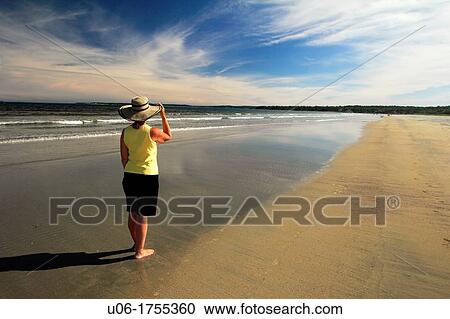 Stock Image - a woman walking on Summerville beach in Nova Scotia Canada. Fotosearch