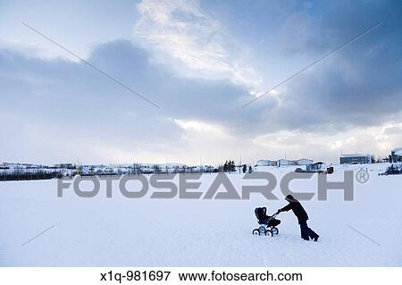 A woman walking with a pram in the snow Hafnarfjordur, Iceland View Large Photo Image Stock Photo - A woman walking with a pram in the snow Hafnarfjordur, Iceland. Fotosearch