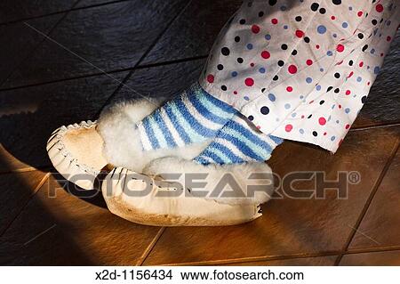 A woman wearing fur-lined moccasin slippers, candy striped socks and polka dot pyjamas with her feet in the sun View Large Photo Image Picture - A woman wearing fur-lined moccasin slippers, candy striped socks and polka dot pyjamas with her feet in the sun. Fotosearch