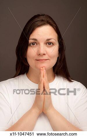 a woman wearing white t-shirt holding her hands together in prayer View Large Photo Image Stock Image - a woman wearing white t-shirt holding her hands together in prayer. Fotosearch