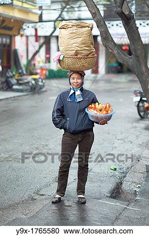 A woman with a large basket on her head selling bread and bananas on the streets of Vietnam View Large Photo Image Stock Image - A woman with a large basket on her head selling bread and bananas on the streets of Vietnam. Fotosearch