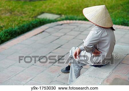 A woman with her hand on her hip wearing a traditional Non La sitting on steps View Large Photo Image Stock Image - A woman with her hand on her hip wearing a traditional Non La sitting on steps. Fotosearch