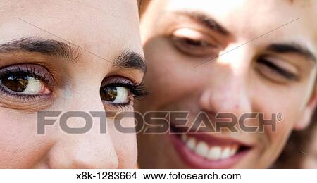 Picture - A woman's eyes look left as her husband looks at her from the background. Fotosearch