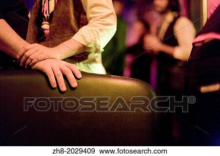 Stock Photo - A woman's hand gently grasps a man's hand in a dark dim romantic setting.. Fotosearch