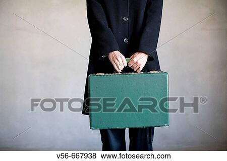 Stock Photo - A woman's torso holding an old suitcase. Fotosearch