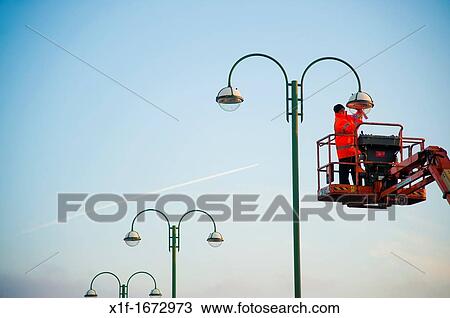 a workman working at height on a high access platform maintaining a street lamp light UK View Large Photo Image Stock Image - a workman working at height on a high access platform maintaining a street lamp light UK. Fotosearch
