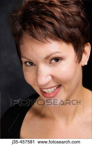 A young 20? s, 30's woman with short red brown hair wearing a black sweater top smiles while looking into camera View Large Photo Image Stock Image - A young 20? s, 30's woman with short red brown hair wearing a black sweater top smiles while looking into camera. Fotosearch