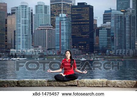 A young Asian woman does the Padmasana Lotus Pose yoga pose along the Stanley Park seawall with the city skyline beyond, Vancouver, British Columbia, Canada View Large Photo Image Stock Photo - A young Asian woman does the Padmasana Lotus Pose yoga pose along the Stanley Park seawall with the city skyline beyond, Vancouver, British Columbia, Canada. Fotosearch