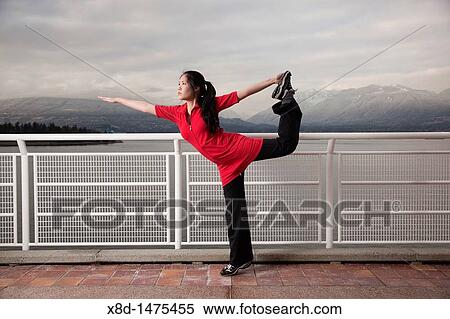 A young Asian woman does the Natarajasana Lord of the Dance yoga pose at Canada Place, Vancouver, British Columbia, Canada View Large Photo Image Stock Photography - A young Asian woman does the Natarajasana Lord of the Dance yoga pose at Canada Place, Vancouver, British Columbia, Canada. Fotosearch