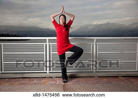 A young Asian woman does the Vrksasana Tree Pose yoga pose at Canada Place, Vancouver, British Columbia, Canada View Large Photo Image Stock Photograph - A young Asian woman does the Vrksasana Tree Pose yoga pose at Canada Place, Vancouver, British Columbia, Canada. Fotosearch