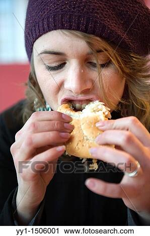 A young, attractive female eating a hamburger at a fast food restaurant. View Large Photo Image Stock Image - A young, attractive female eating a hamburger at a fast food restaurant.. Fotosearch