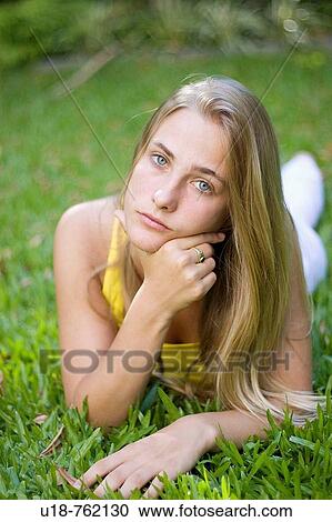 a young blonde girl laying down in the grass with a yellow shirt View Large Photo Image Stock Image - a young blonde girl laying down in the grass with a yellow shirt. Fotosearch