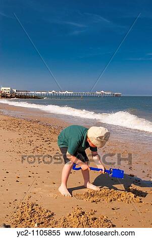 A young boy child playing in the sand on Southwold beach with the pier behind in Suffolk Uk View Large Photo Image Stock Photography - A young boy child playing in the sand on Southwold beach with the pier behind in Suffolk Uk. Fotosearch