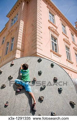 A young boy free climbing on a practice wall in the city of Merano, South Tyrol, Trentino Alto Adige, Italy View Large Photo Image Stock Photography - A young boy free climbing on a practice wall in the city of Merano, South Tyrol, Trentino Alto Adige, Italy. Fotosearch