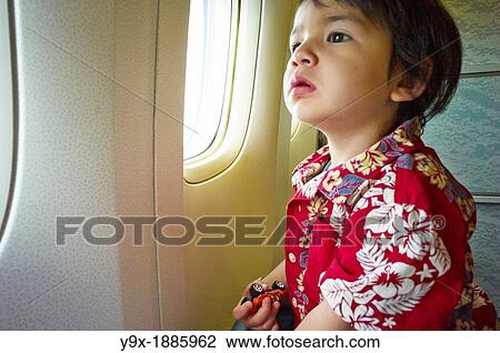 A young boy in a Hawaiian shirt looking out of a plane window View Large Photo Image Stock Image - A young boy in a Hawaiian shirt looking out of a plane window. Fotosearch