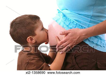 Stock Image - A young boy kisses his mothers pregnant stomache, isolated on white background. Fotosearch